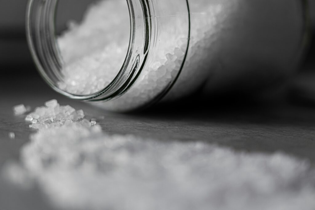 pexels photo 3693294 3693294 Detailed image of rock salt pouring out from a glass jar with a selective focus effect.